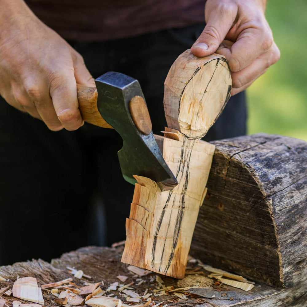 Person splitting wood with an axe outdoors