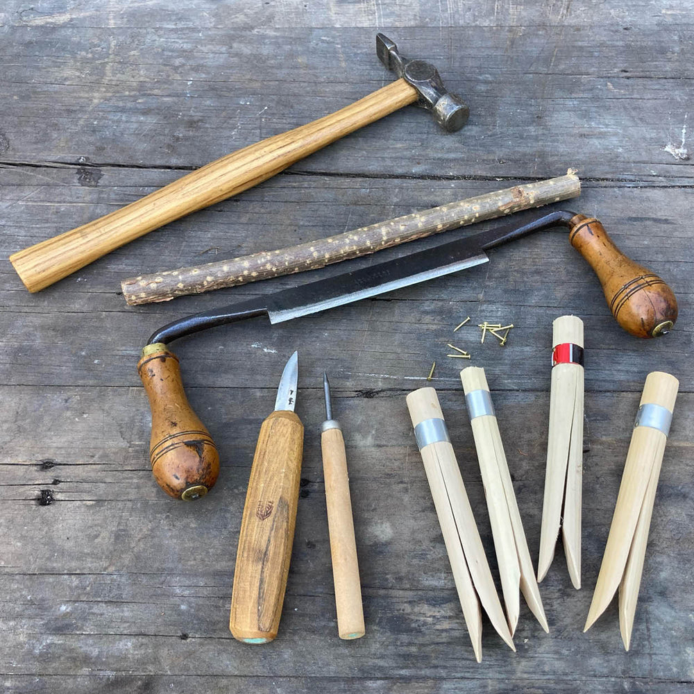 Set of woodworking tools including a hammer, chisels, and a saw on a wooden surface.