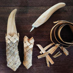Wooden tool in a willow bark pouch on a wooden surface