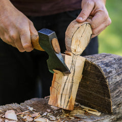 Person splitting wood with an axe outdoors