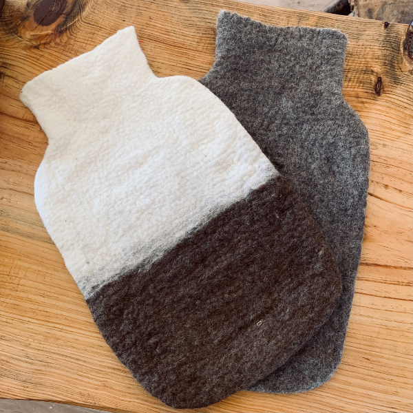 Two felt hot water bottles with different color patterns on a wooden surface