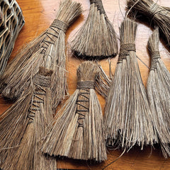 Collection of brooms with straw bristles on a wooden surface
