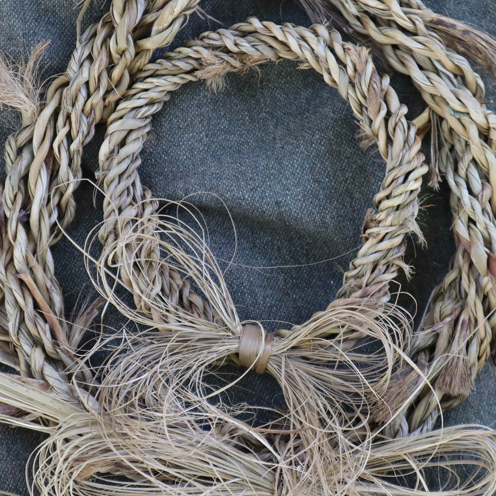 Woven ti kouka wreath with bow on a textured surface