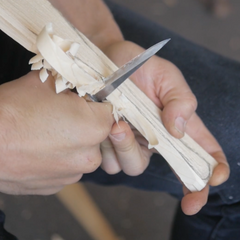 A person is carving a greenwood spatula with a knife and an axe, focusing on the detailed craftsmanship.